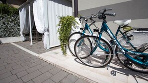 A blue bicycle parked next to a white building with a white awning. - Sweet Home (Treviso)
