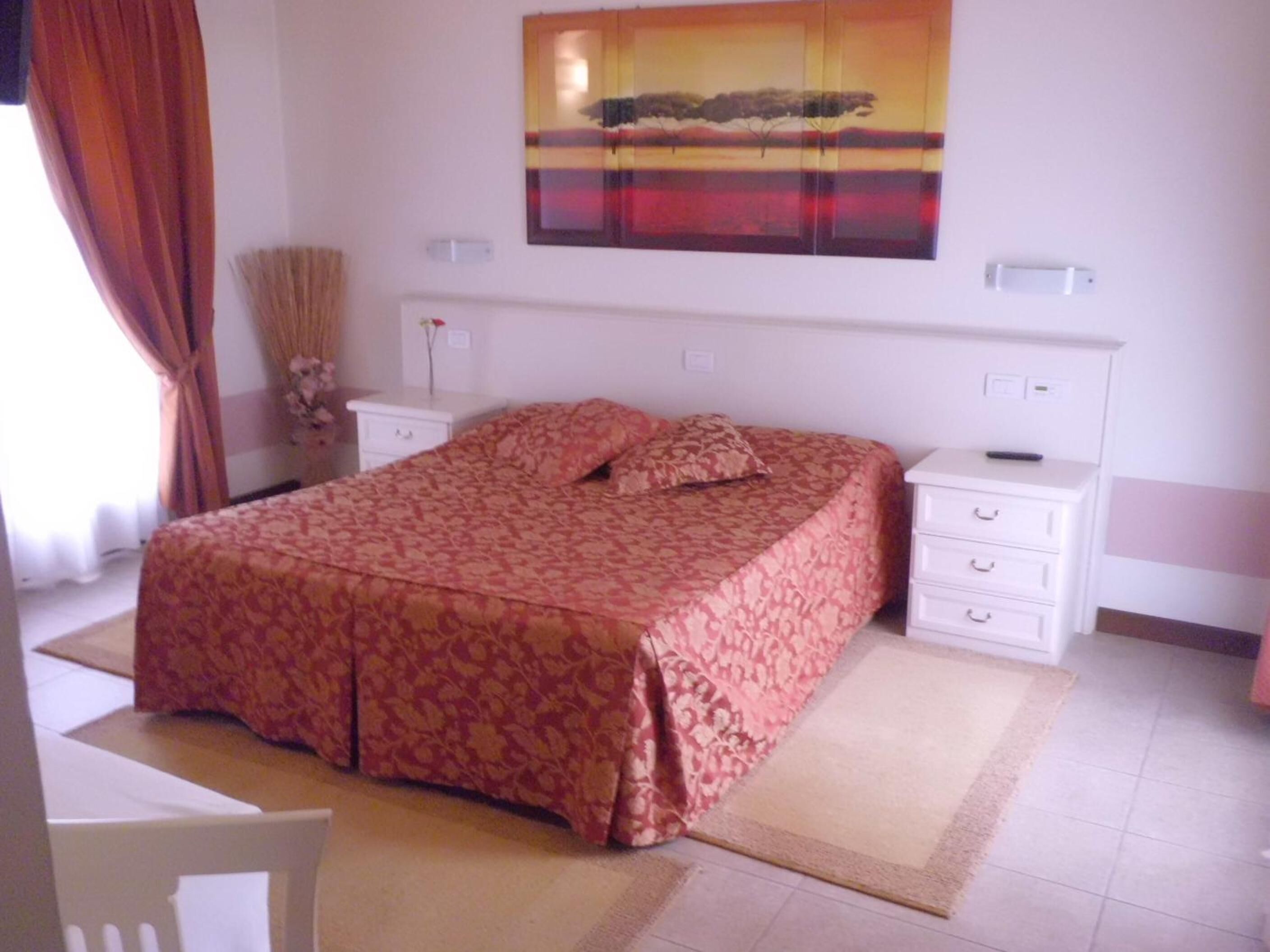 Una camera da letto con un letto, comodini, una cassettiera e un quadro appeso al muro.