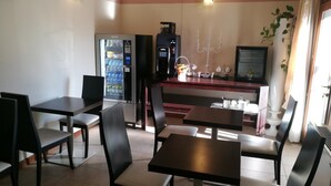A restaurant with tables and chairs, a vending machine, a coffee machine, and a counter with a display screen. - Sweet Home (Treviso)
