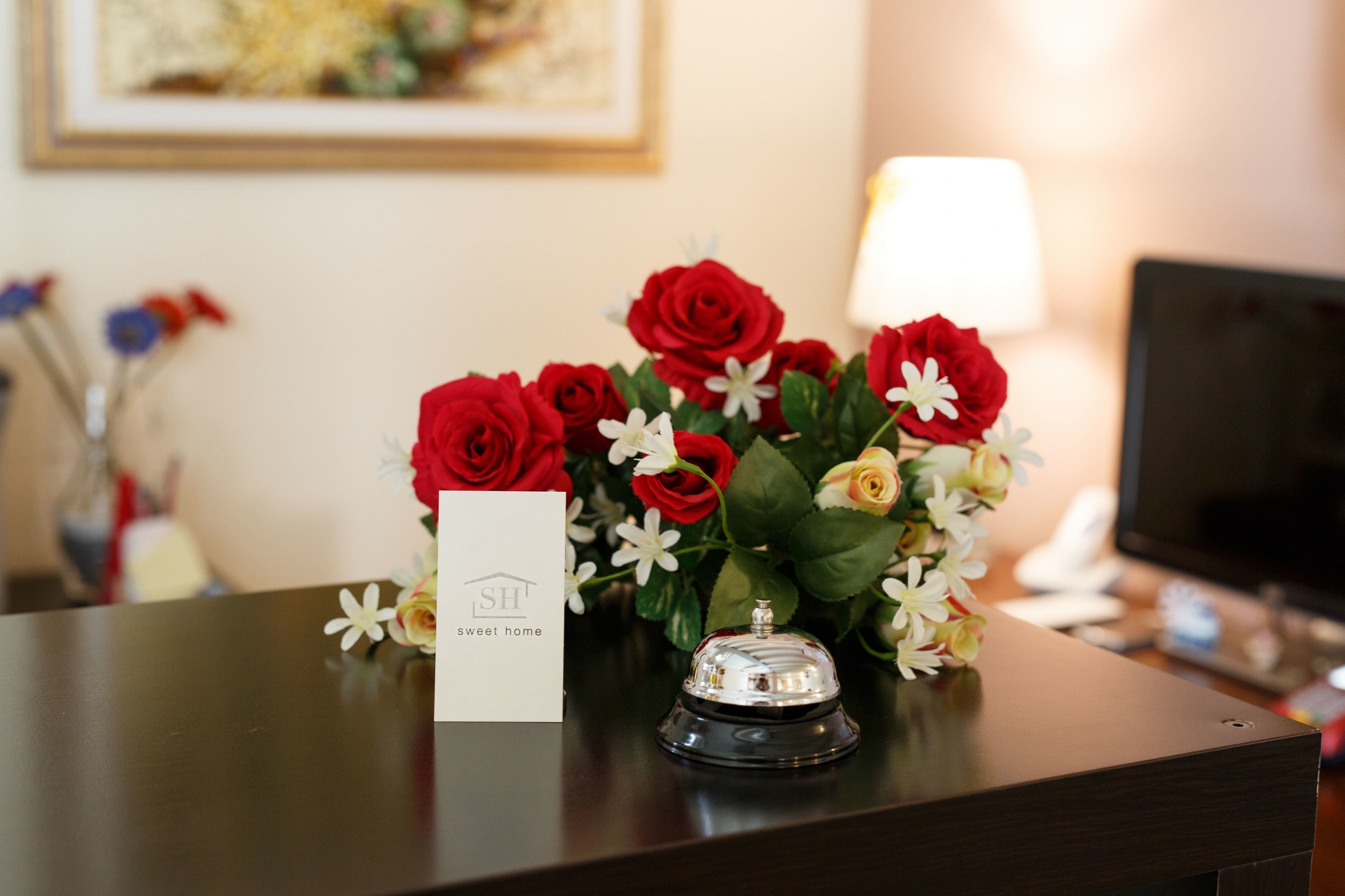 A reception desk with a floral arrangement, a bell, and a business card.
