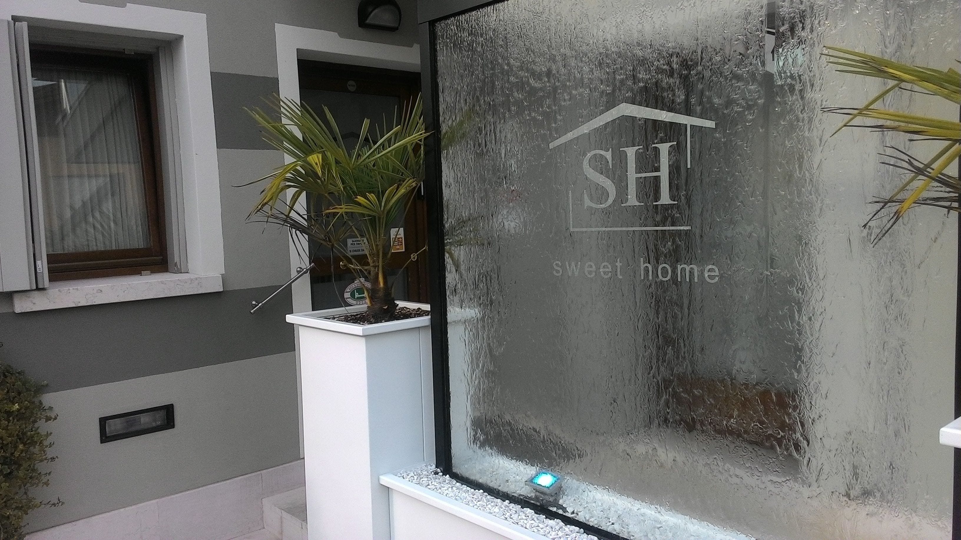 Eine moderne Gebäudefassade mit einem satinierten Fenster, das das Logo "SH Sweet home" zeigt.