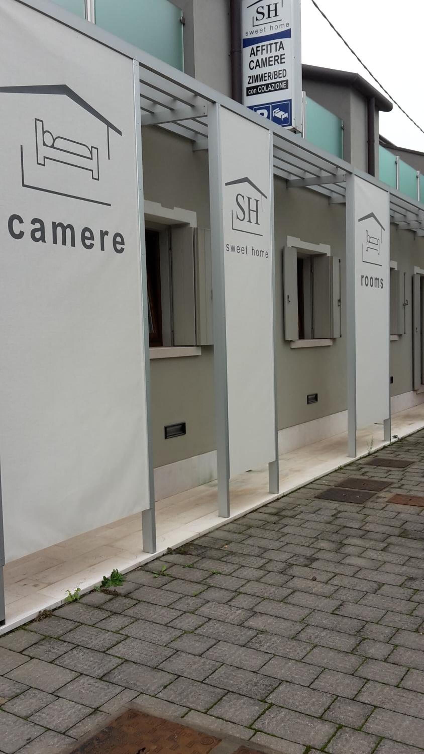 Une rangée de chambres dont les panneaux indiquent « cameri » et « rooms » pour indiquer qu’il s’agit d’hébergements.