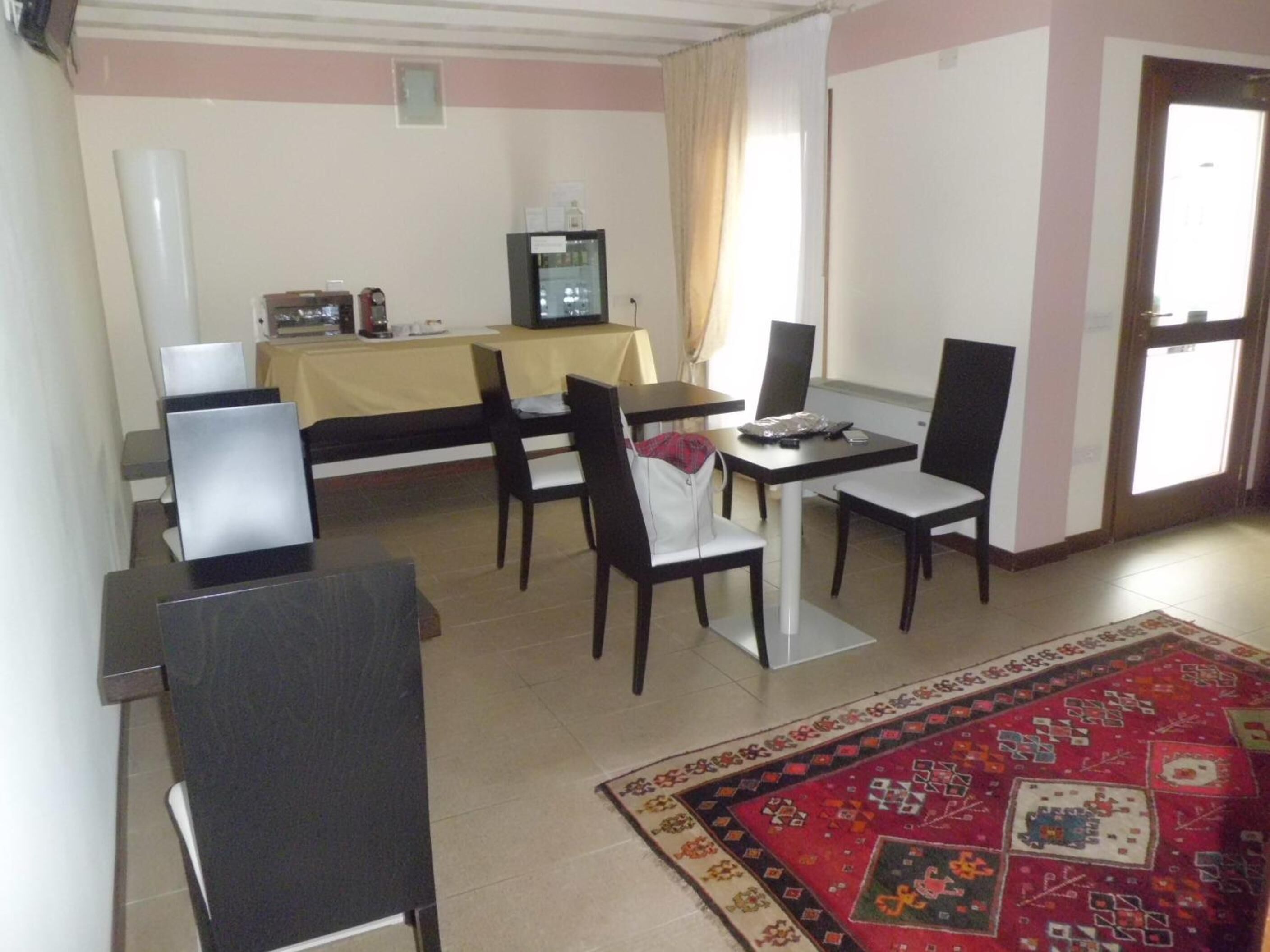 A room with a desk, two chairs, a small table, a refrigerator, and a television.