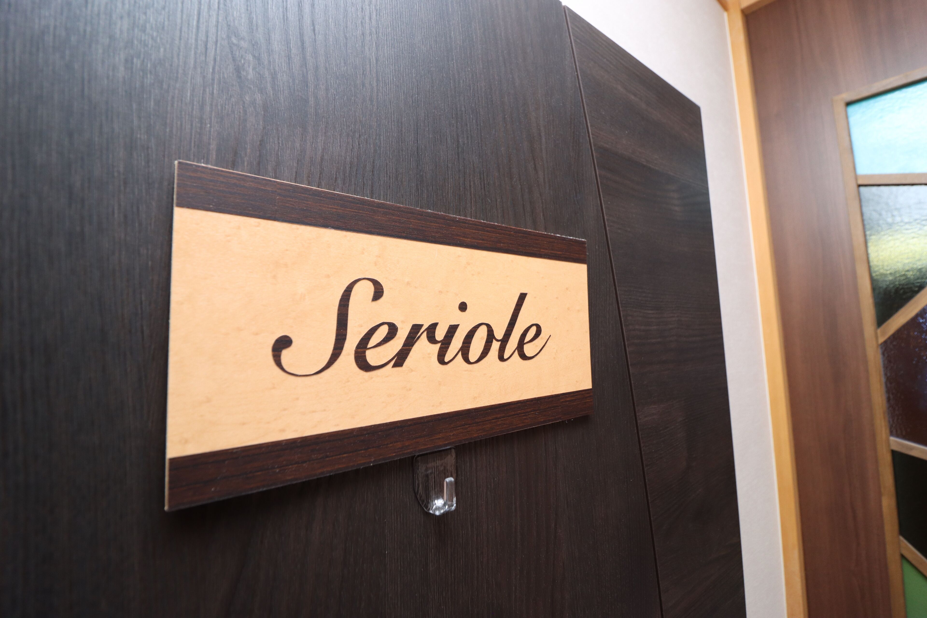 A wooden sign with the word "Seriole" mounted on a dark wooden wall.