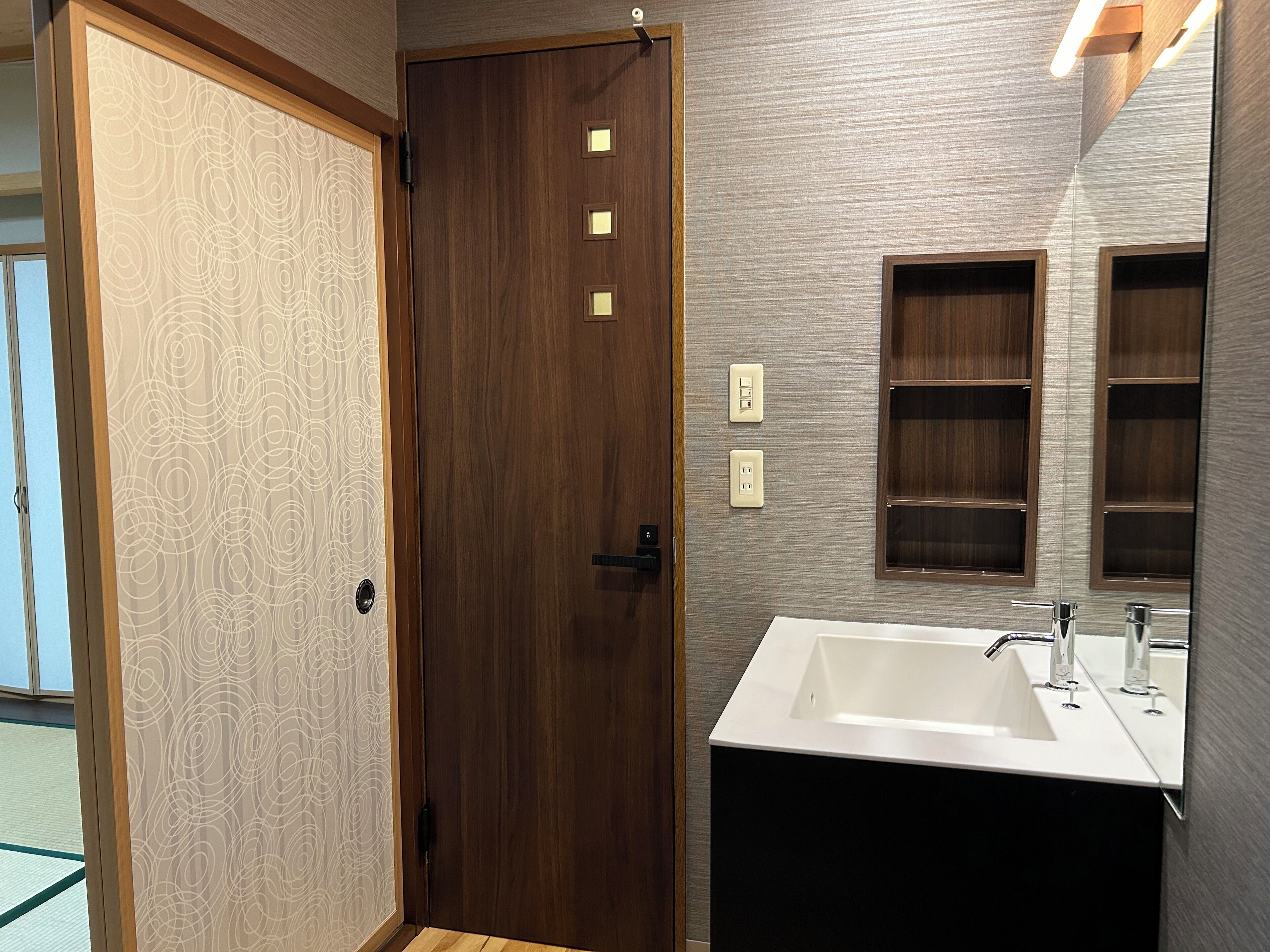 A bathroom with a wooden door, a white sink, and a mirror.