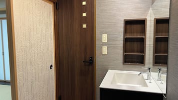 A bathroom with a wooden door, a white sink, and a mirror.