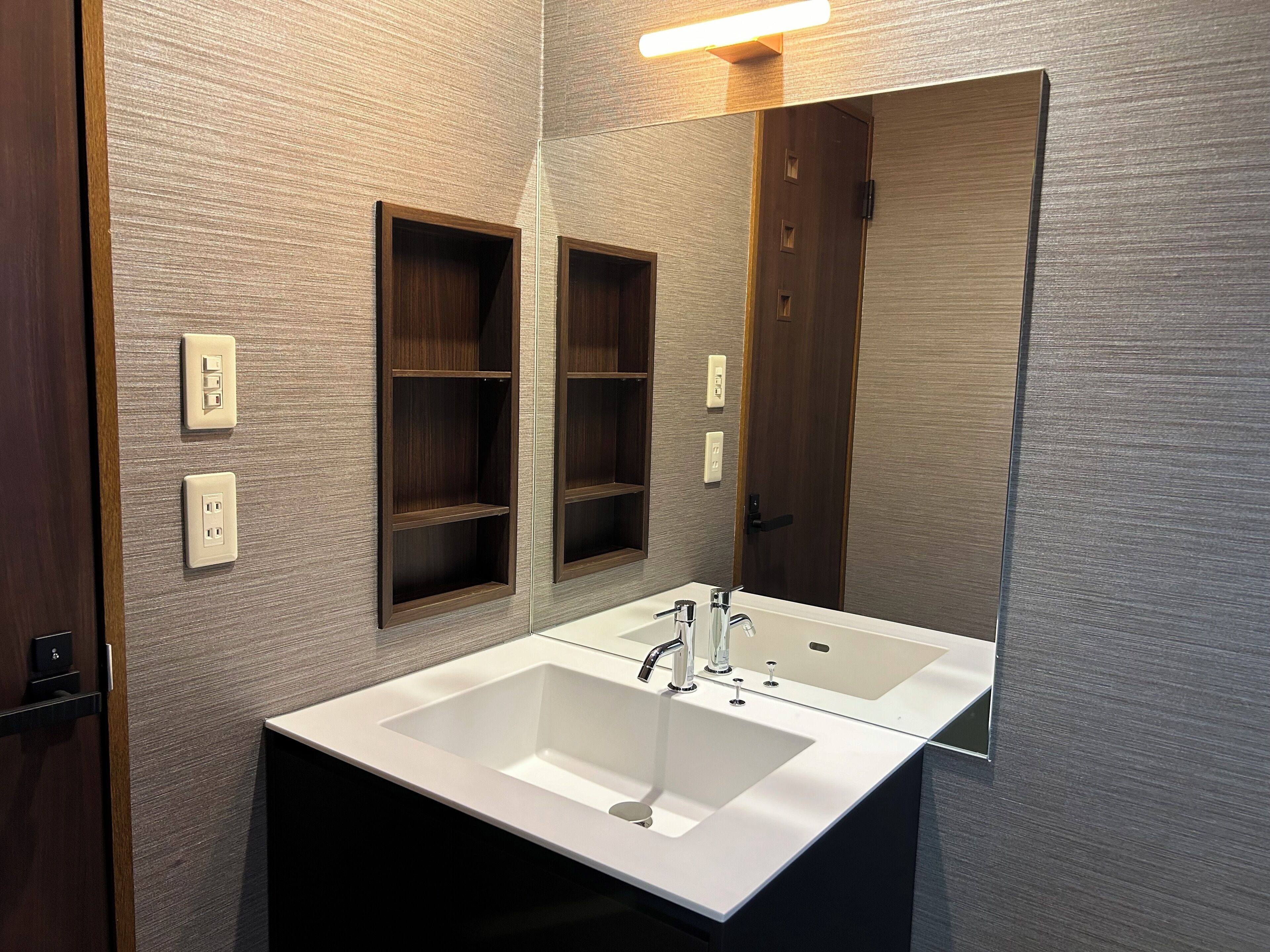 A bathroom with two sinks, a mirror, and wooden shelves.