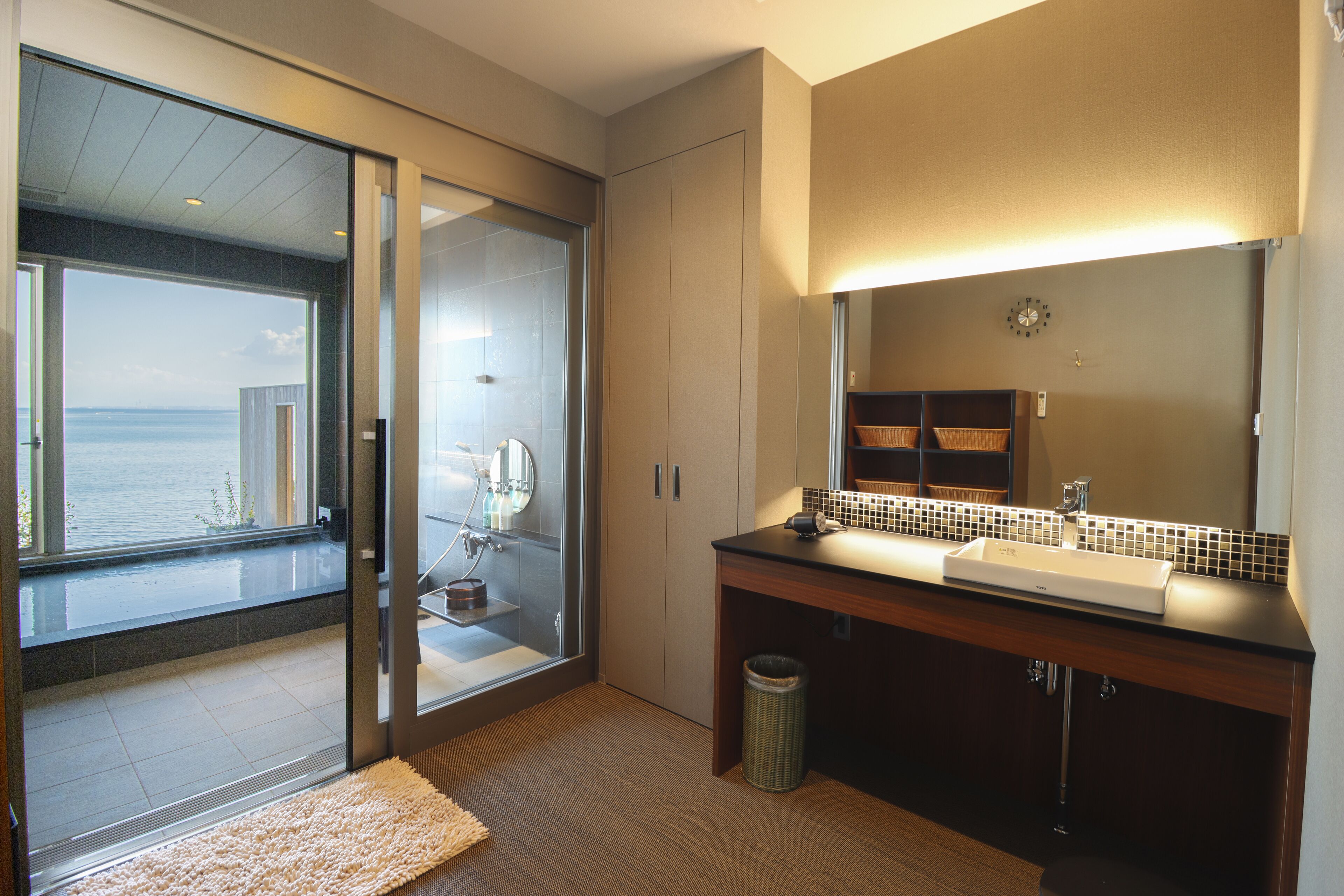Un baño moderno con un espejo grande, un lavamanos y una zona de ducha.