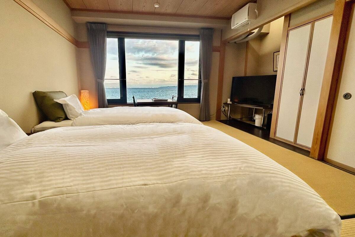 Una habitación de hotel con dos camas, televisión y vista al mar.