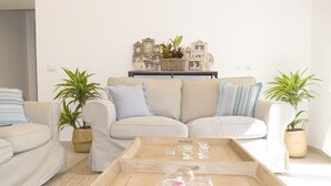 Una sala de estar con dos sofás, una mesa de centro y objetos decorativos en un aparador.