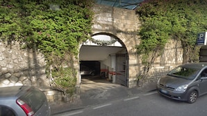 Un arco de piedra que da acceso a un edificio con zona de estacionamiento.