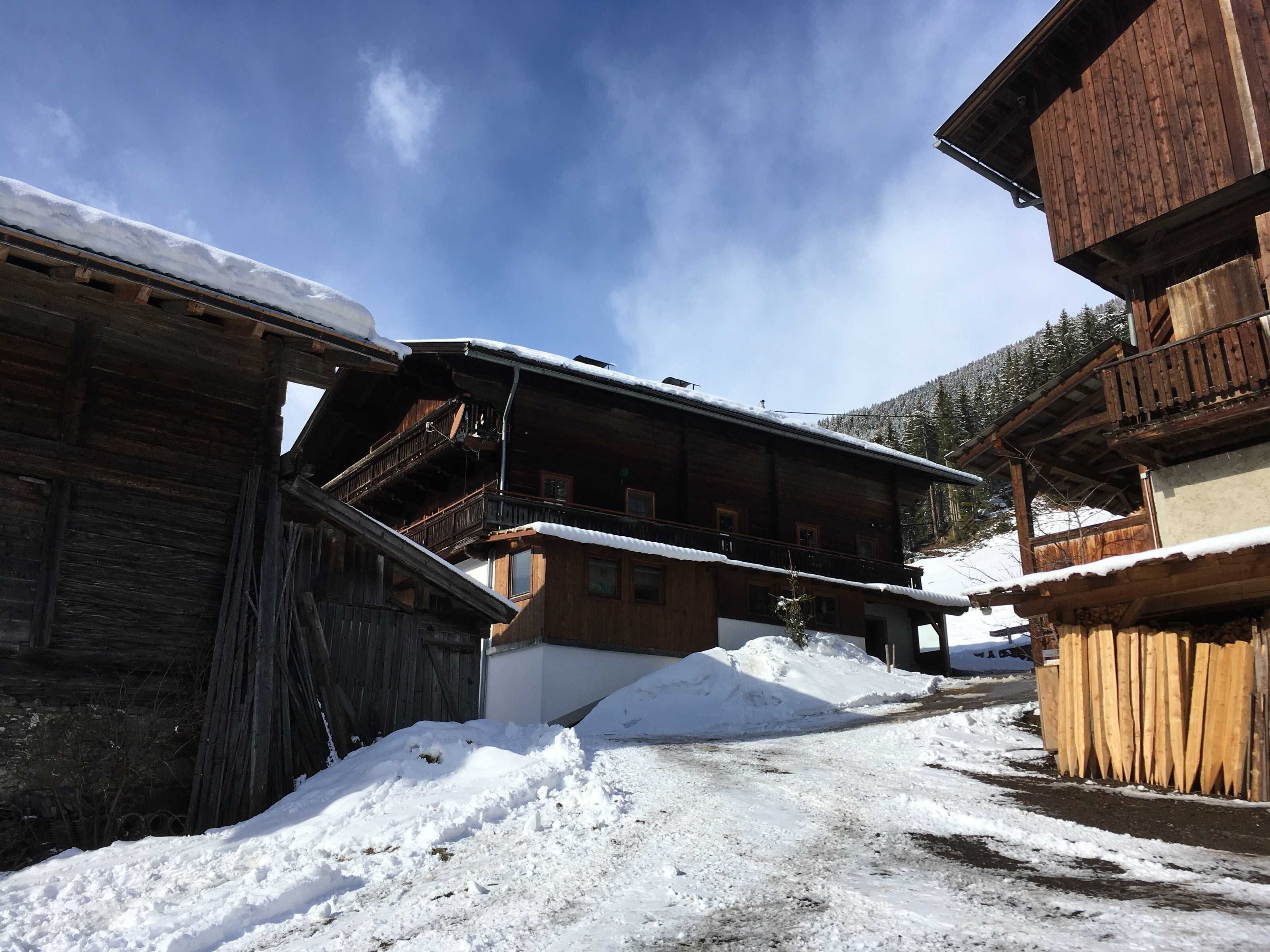 A wooden building with a balcony, a snow-covered ground, and a clear sky.
