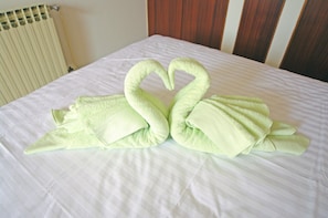 A bed with a white sheet and two green towels arranged in the shape of swans. - Kuntrada 45 with heated pool and kids pool (Fazana)
