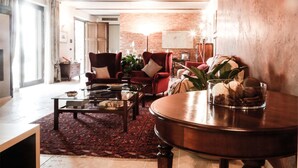 Una sala de estar acogedora con un sofá rojo, una mesa de centro y una mesa redonda de madera con un cuenco decorativo.