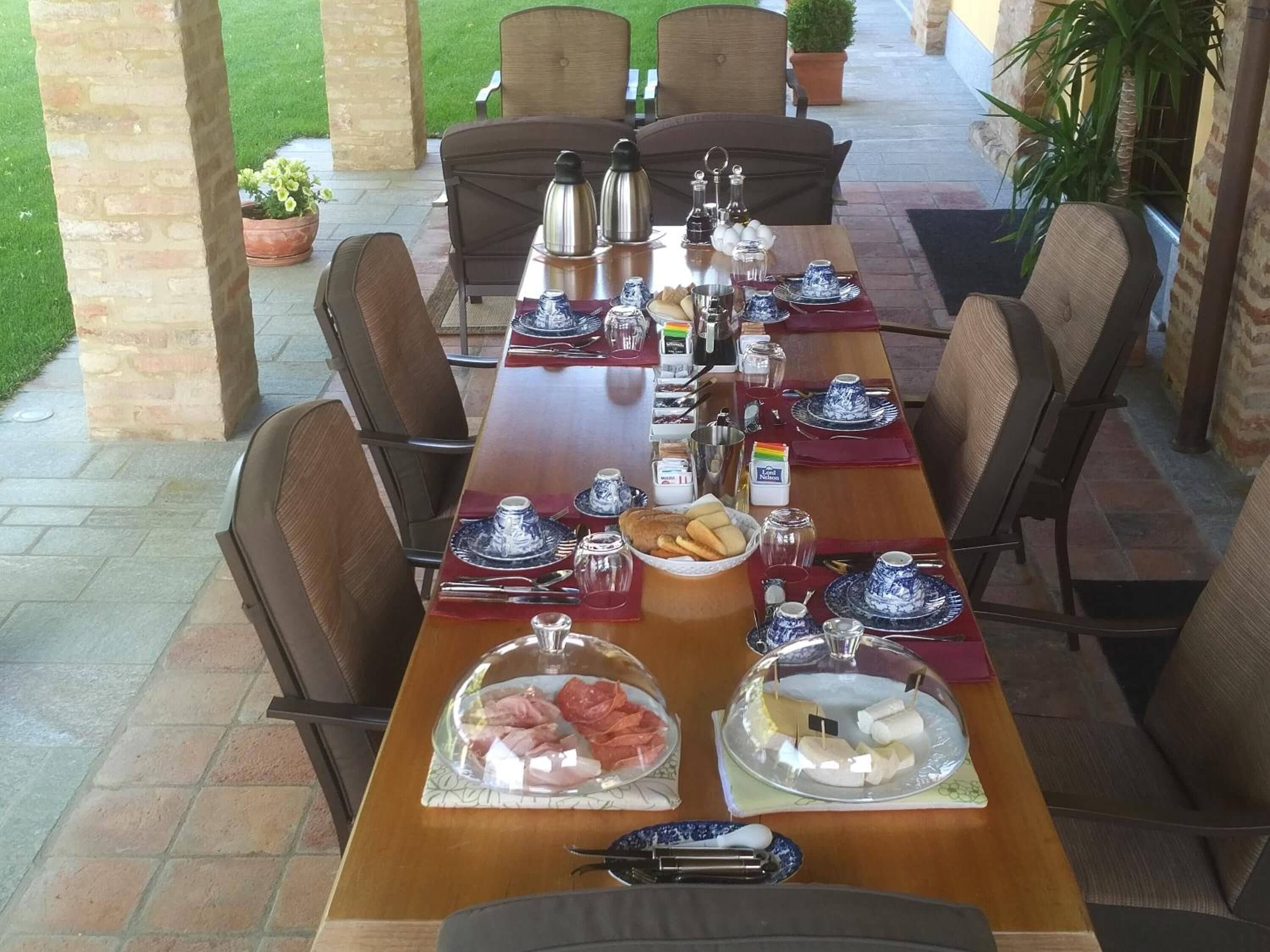 Een lange eettafel gedekt voor een maaltijd, met stoelen, diverse gerechten en bijbehorende sauzen.