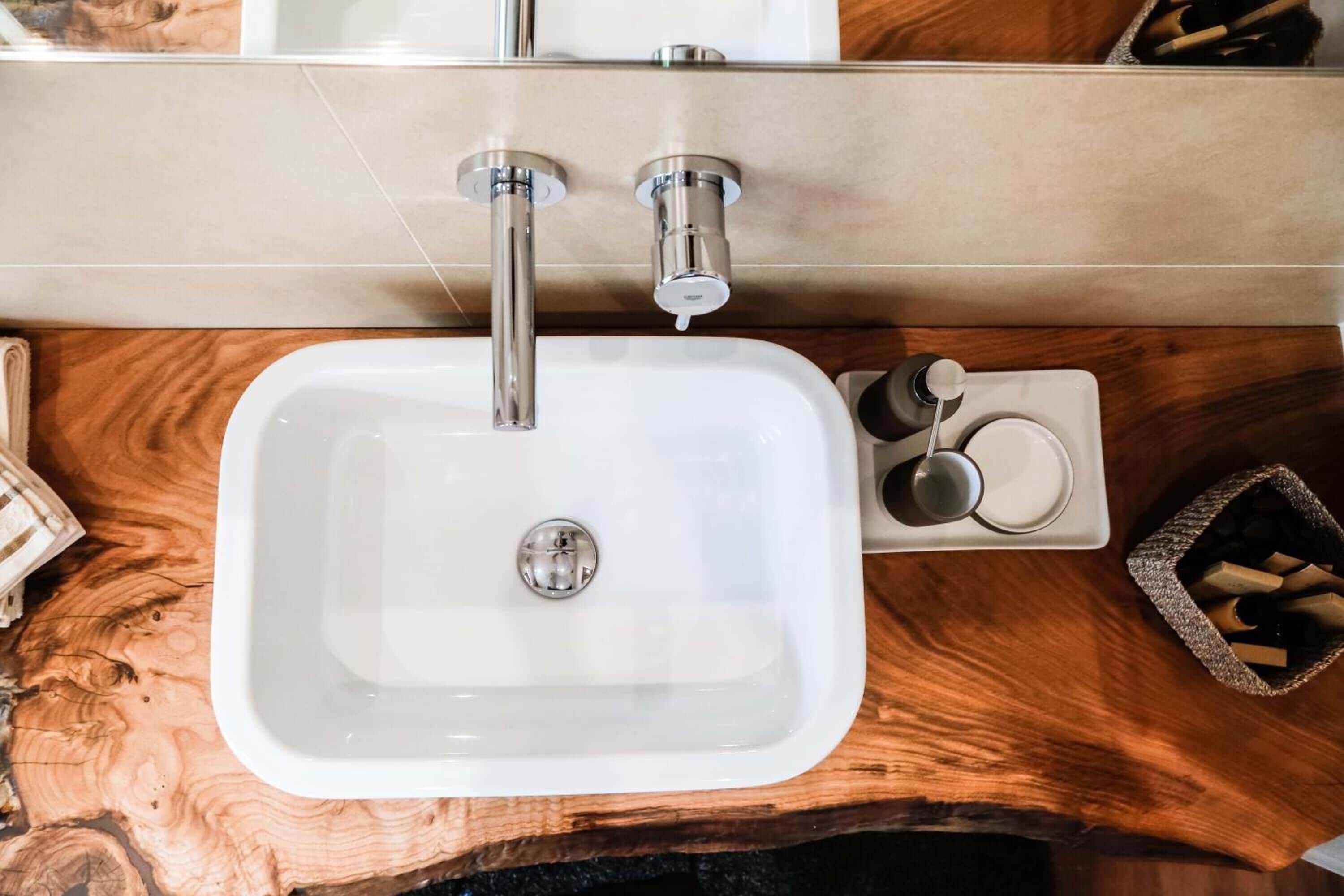A bathroom with a white sink, a wooden vanity, and a mirror above the sink.