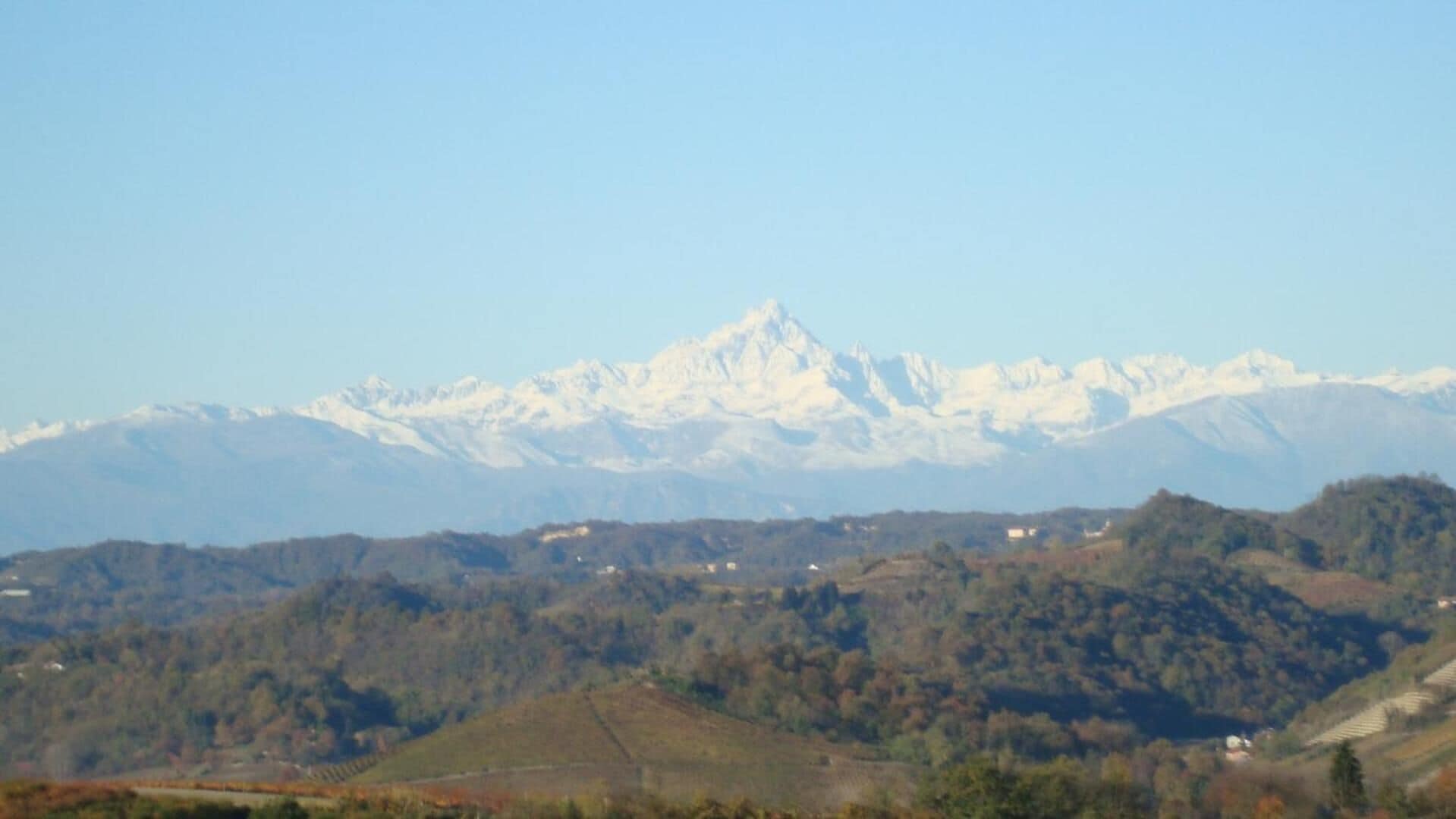 A mountainous landscape with snow-capped peaks and a valley with scattered buildings.