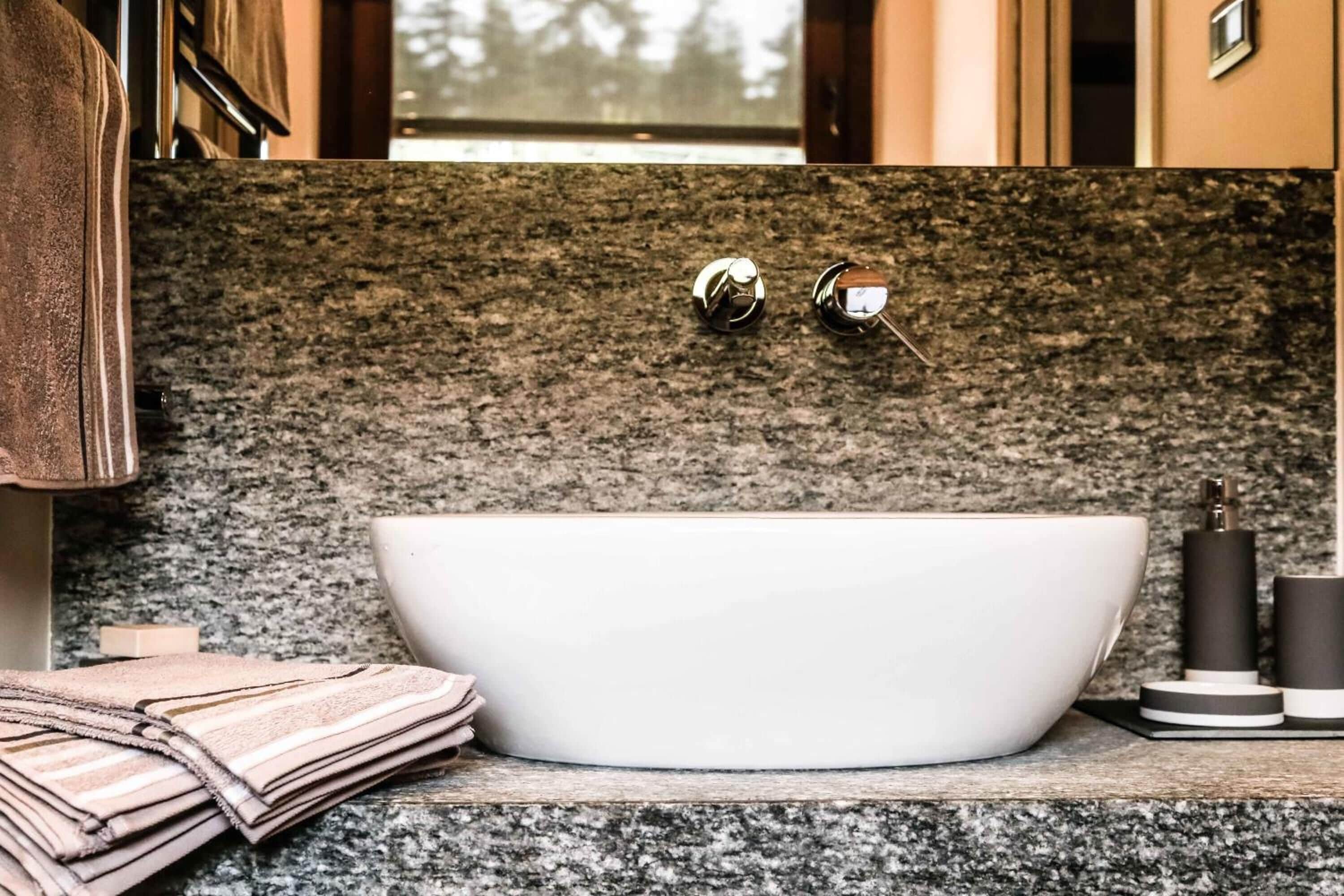 Une salle de bain moderne avec une baignoire sur pieds, un comptoir en granit et un porte-serviettes.