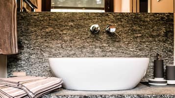 Une salle de bain moderne avec une baignoire sur pieds, un comptoir en granit et un porte-serviettes.