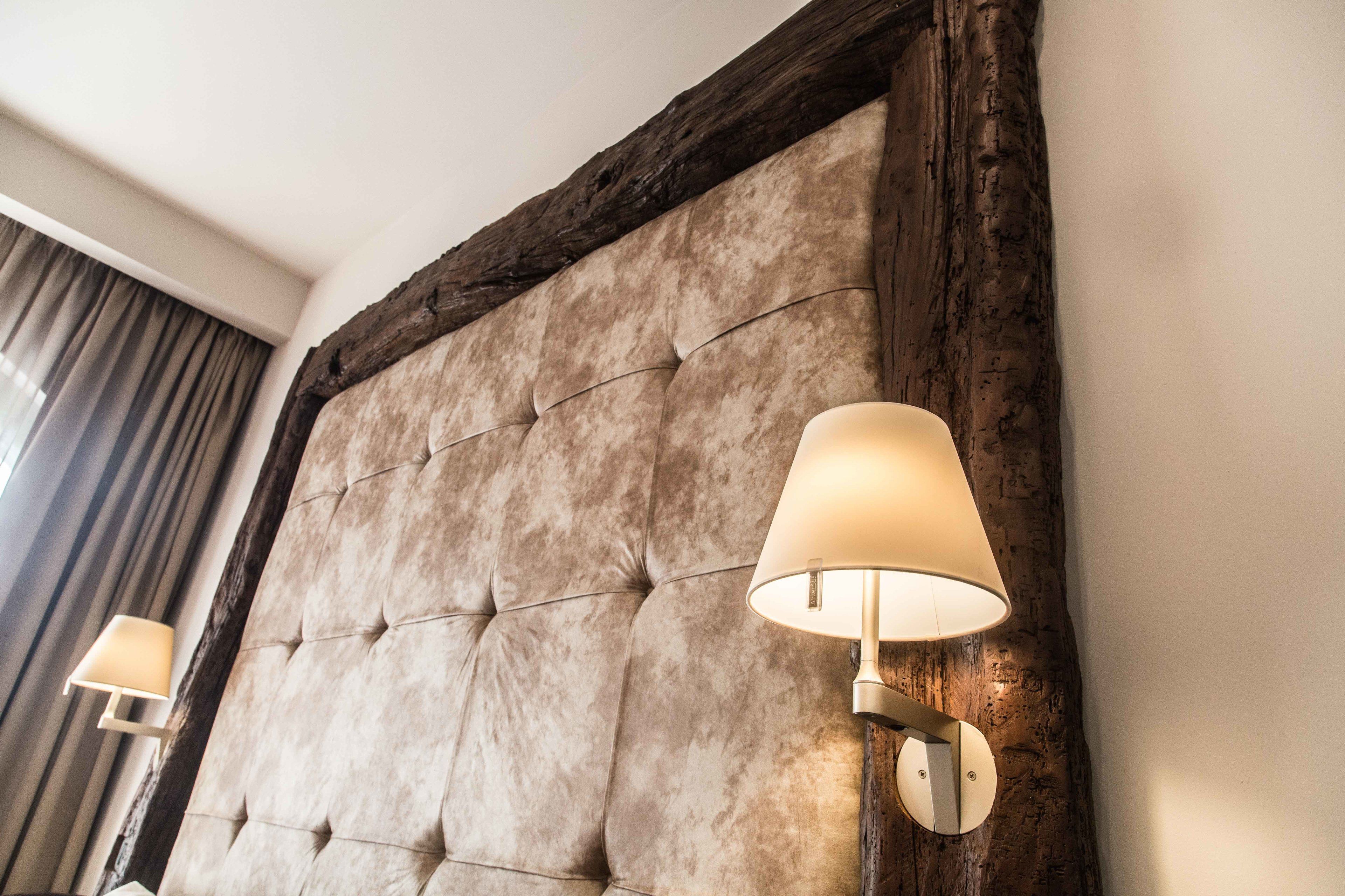 A tufted headboard with a wooden frame and two wall-mounted lamps.