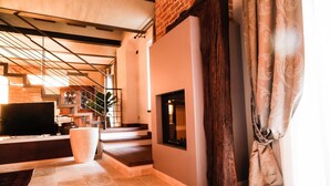 Una sala de estar moderna con chimenea, televisor y una escalera que conduce a otro nivel.