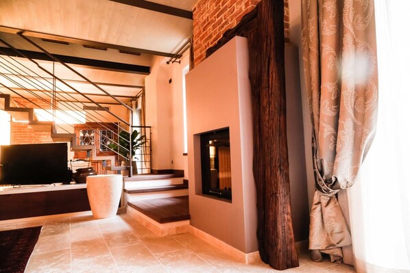 Una sala de estar moderna con chimenea, televisor y una escalera que conduce a otro nivel.