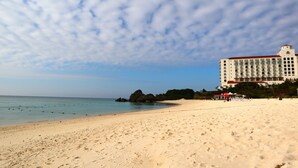 Una playa con un hotel al fondo.