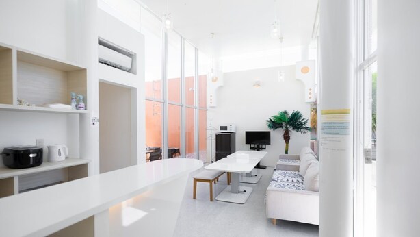 Una cocina moderna y bien iluminada con armarios blancos, una mesa de comedor y un sofá.