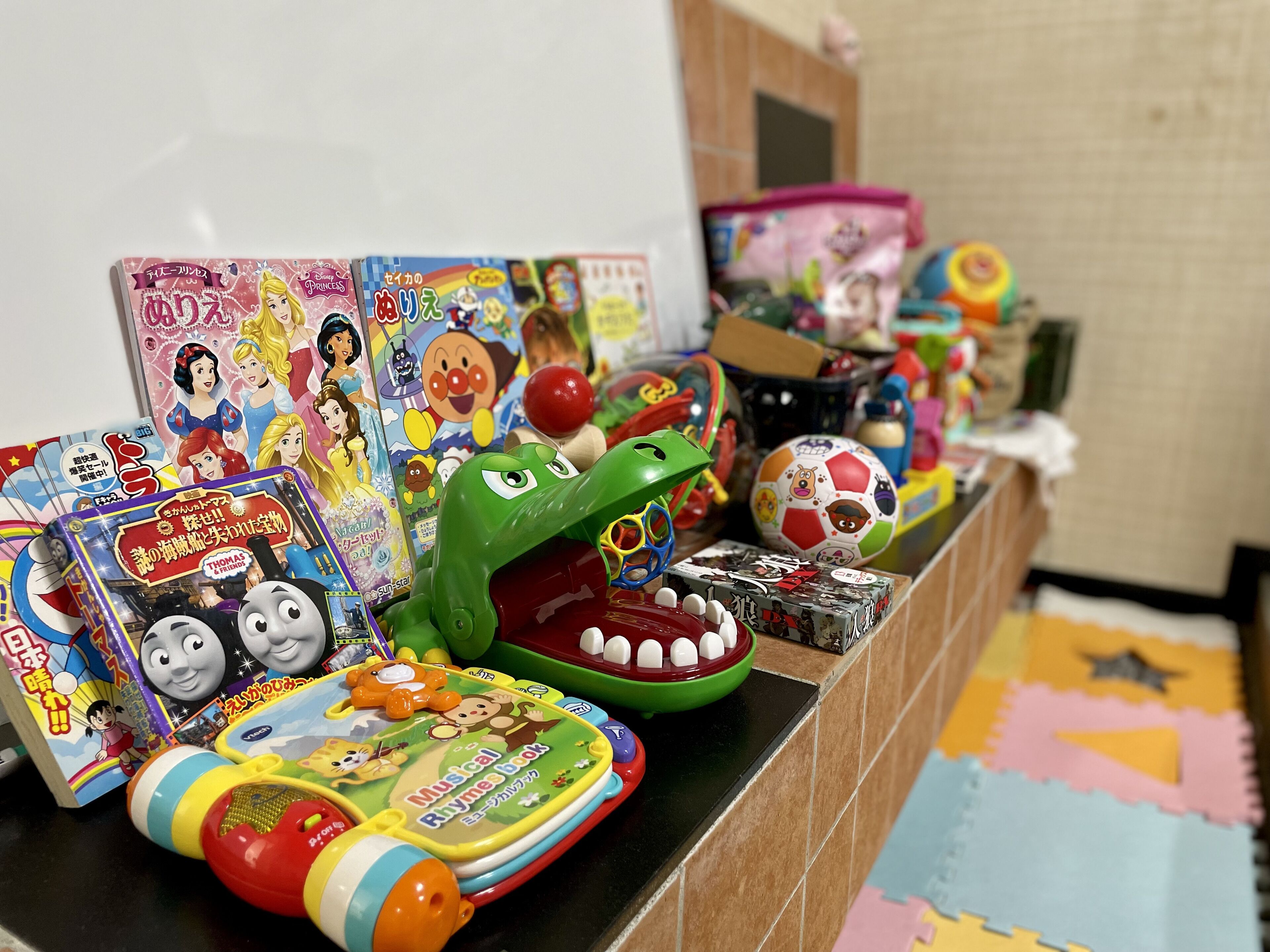 Une variété de jouets et de livres pour enfants sont exposés sur une étagère.
