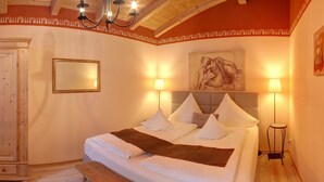 Ein helles Schlafzimmer mit einem großen Bett, zwei Nachttischlampen, einer hölzernen Bank und einem Bild an der Wand.