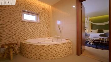 A modern bathroom with a freestanding bathtub, a small window, and a view of a dining area.