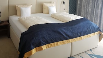A hotel room with a large bed, a headboard, and a patterned wall.