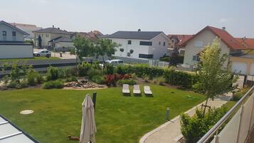 A residential area with a well-maintained lawn, a few lounge chairs, and a small garden area with rocks and plants.