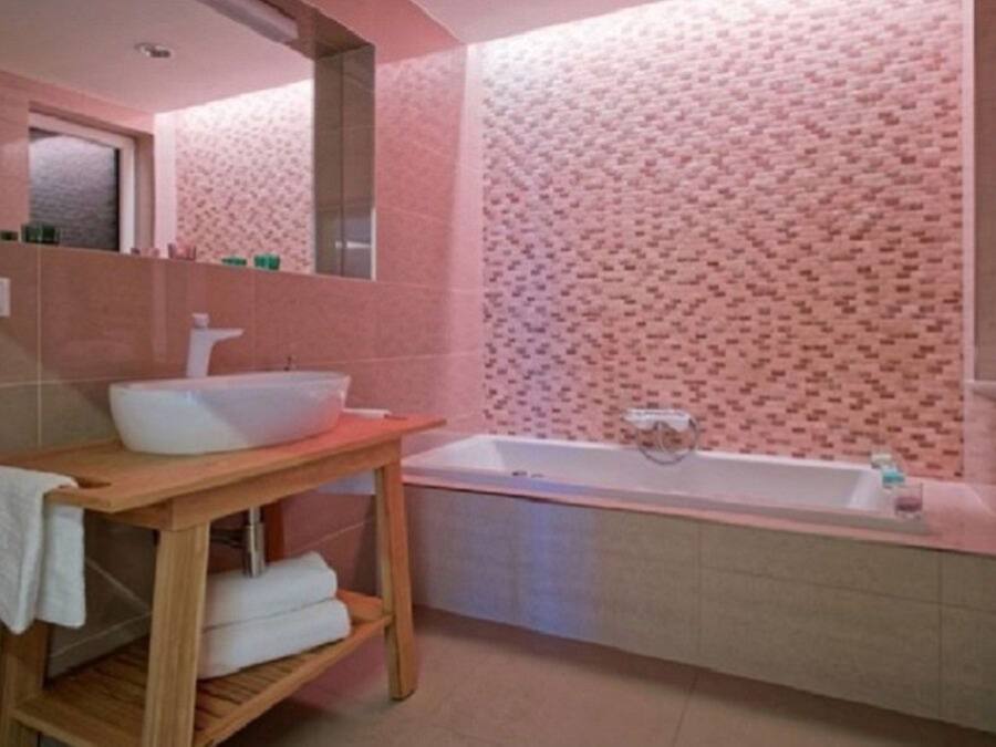 A bathroom with a wooden vanity, a white sink, and a bathtub.