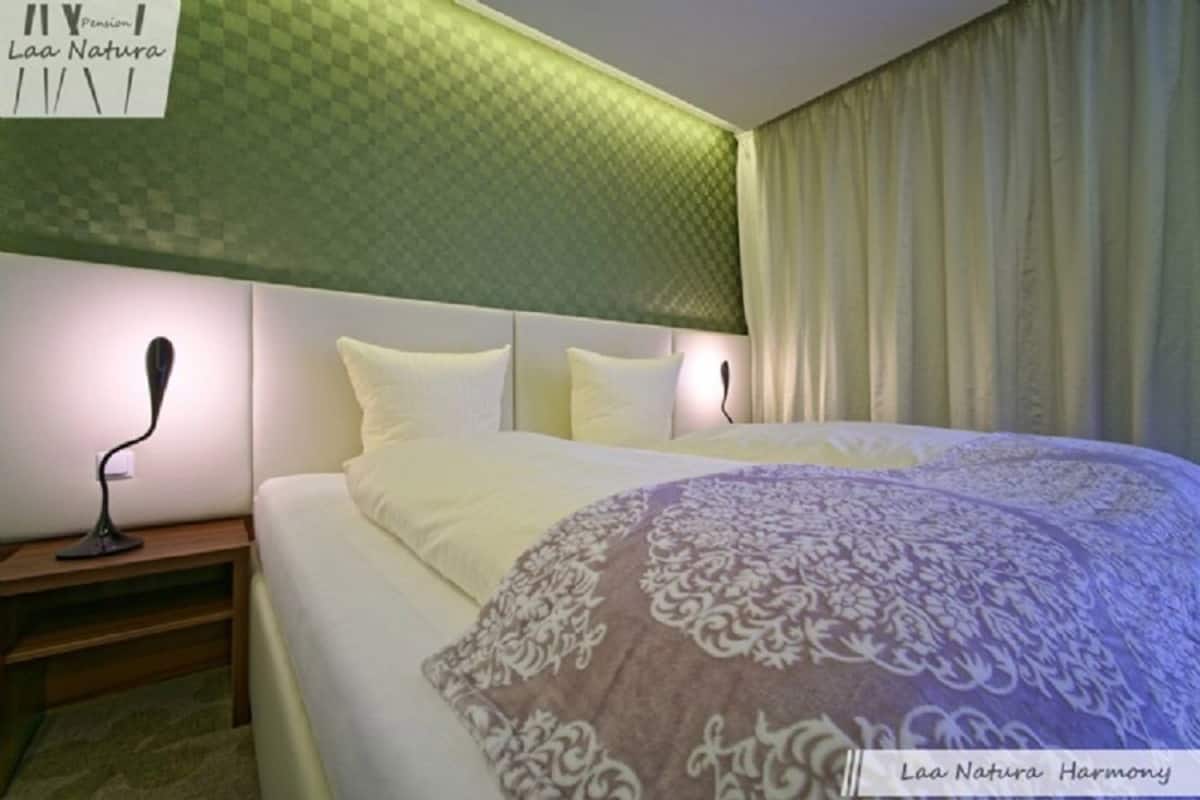 Une chambre d’hôtel avec un lit, une table de chevet et une lampe fixée au mur.