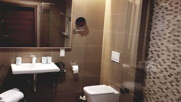 Ein modernes Badezimmer mit Waschbecken, Spiegel, Toilette und Dusche.
