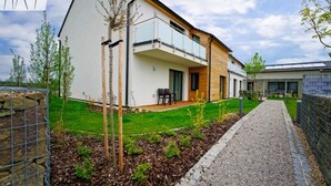 A modern two-story house with a balcony, a well-maintained lawn, and a gravel path. - Pension Laa Natura (Laa an der Thaya)