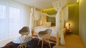 A bedroom with a canopy bed, two chairs, a glass table, and a view of the outdoors. - Pension Laa Natura (Laa an der Thaya)