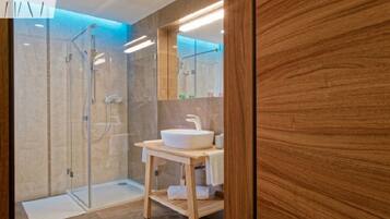 A modern bathroom with a glass-enclosed shower, a wooden vanity with a sink, and a mirror above the vanity.