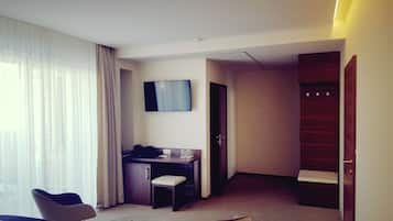 A hotel room with a bed, a desk, a chair, a television, and a wardrobe.