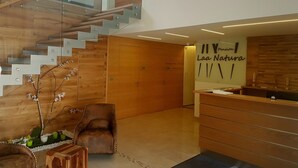 A modern interior with a wooden staircase, a reception desk, and a sign reading "Laa Natura". - Pension Laa Natura (Laa an der Thaya)