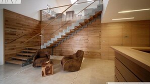 A modern lobby with a wooden staircase, leather chairs, and a reception desk. - Pension Laa Natura (Laa an der Thaya)