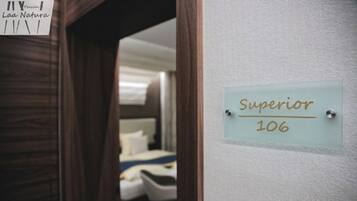 A hotel room with a bed, a small table, and a chair. There is a sign on the wall that reads "Superior 106".