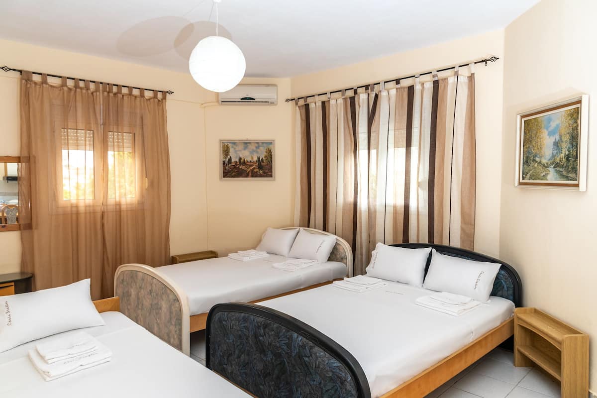 A hotel room with two single beds, a wooden nightstand, a small table, and a ceiling light.