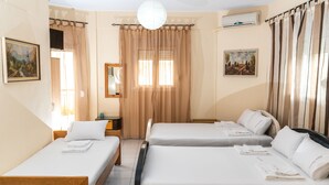 A hotel room with two single beds, a large window with curtains, a flat-screen TV, and artwork on the walls. - Chris Apartments (Kassandra)