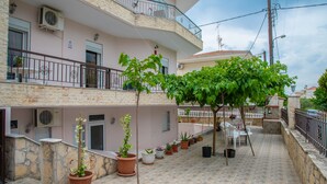 A residential building with a balcony, potted plants, and a tiled patio area. - Chris Apartments (Kassandra)