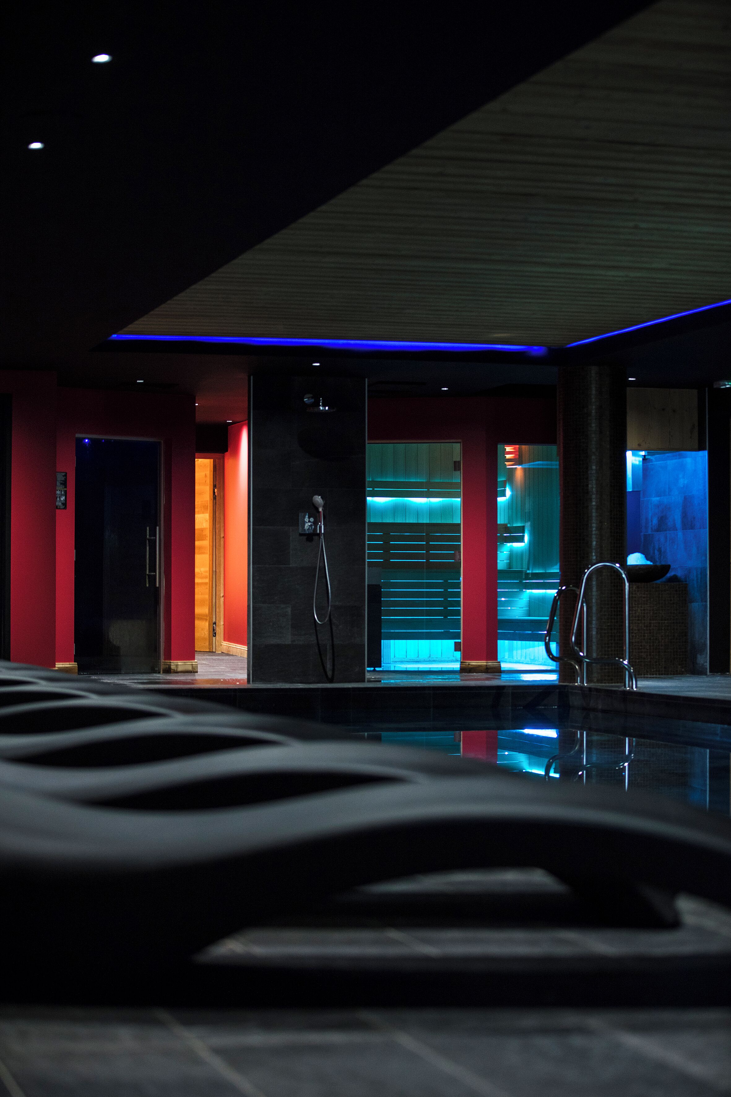 A modern hotel lobby with a reception desk, a shower area, and a pool.