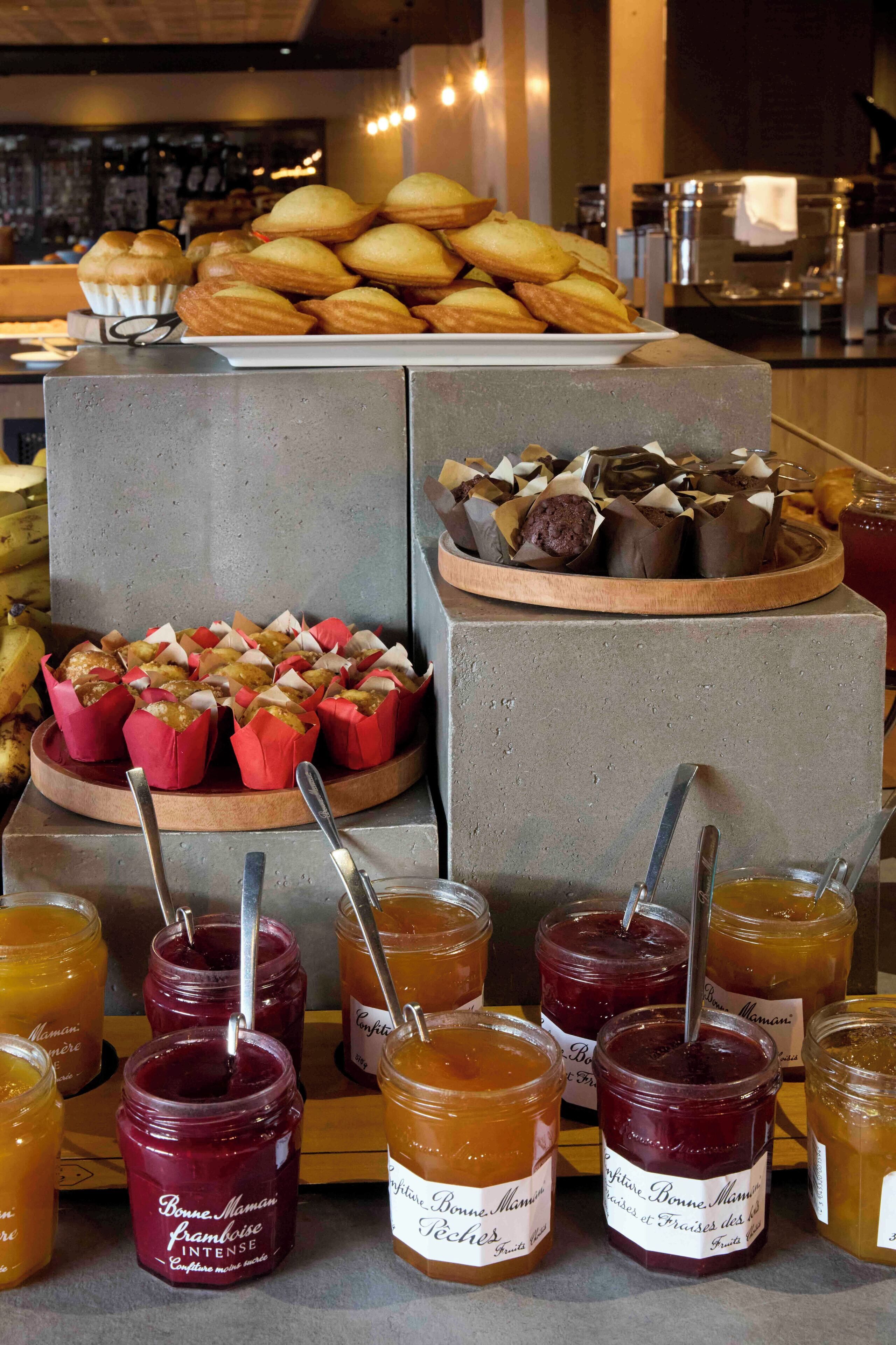 Una exhibición de comida con pasteles, una tarta de frutas y frascos de mermelada.