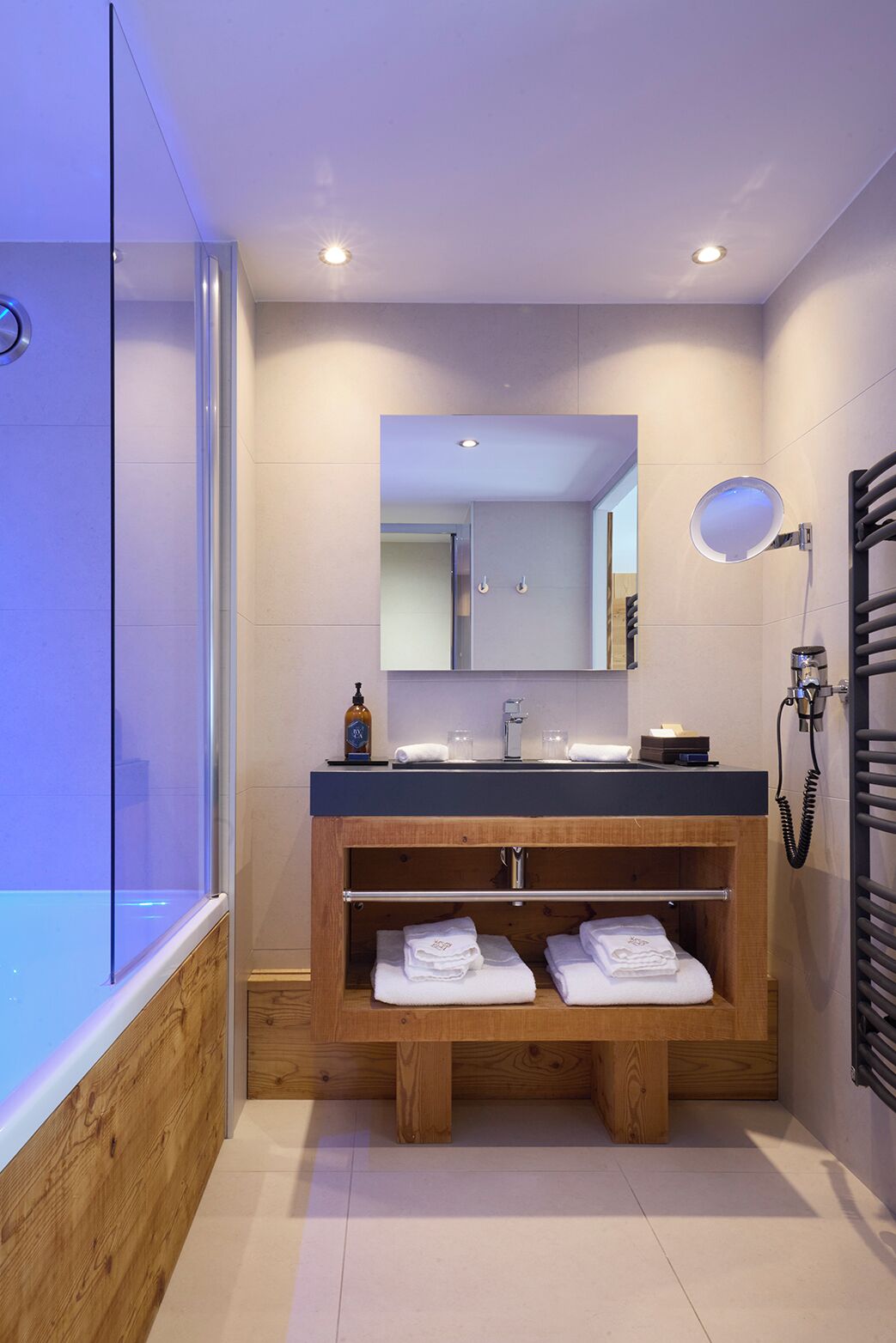 Une salle de bain moderne avec une douche à parois de verre, un meuble-lavabo en bois avec un miroir et un porte-serviettes.