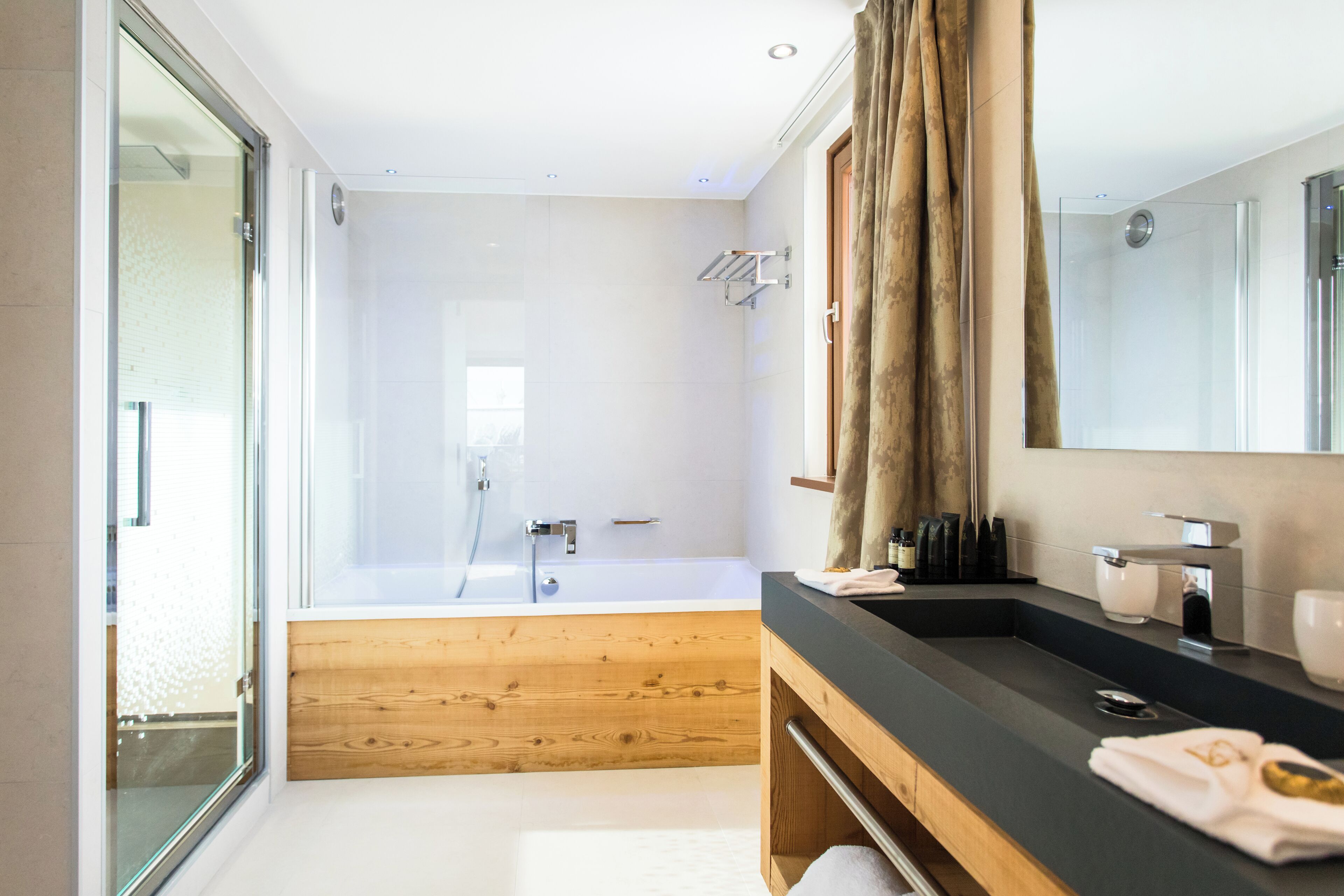 Un baño moderno con ducha de vidrio, tocador de madera y un espejo grande.